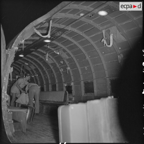 Deux parachutistes rangent les bagages des réfugiés dans un avion.