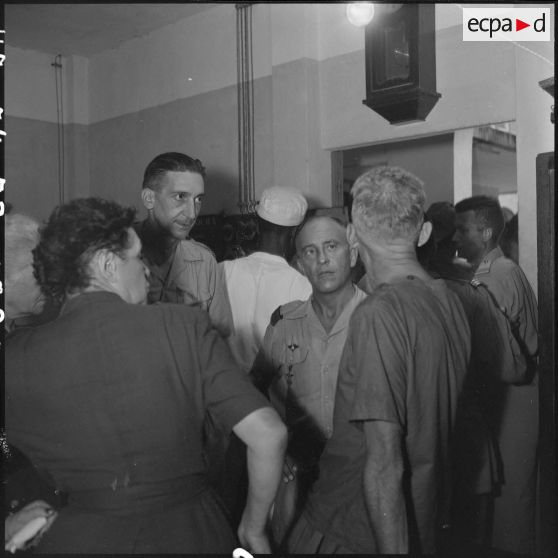 Lors d'une visite médicale organisée au retour des officiers supérieurs prisonniers à Diên Biên Phu, un prisonnier de guerre discute avec des officiers et deux femmes.