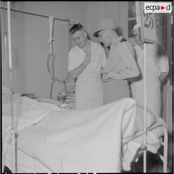 Le général Ely, commissaire général de France et commandant en chef en Indochine, et un médecin-capitaine de l'hôpital militaire Lanessan au chevet d'un homme hospitalisé.