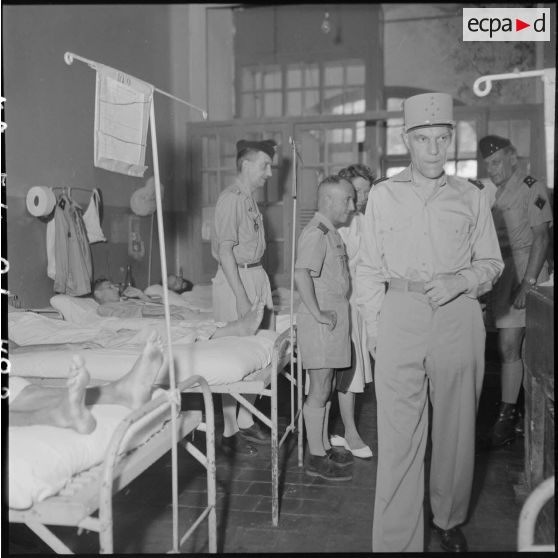 Le général Ely (au premier plan), commissaire général de France et commandant en chef en Indochine, rend visite à des hommes hospitalisés à l'hôpital militaire Lanessan.