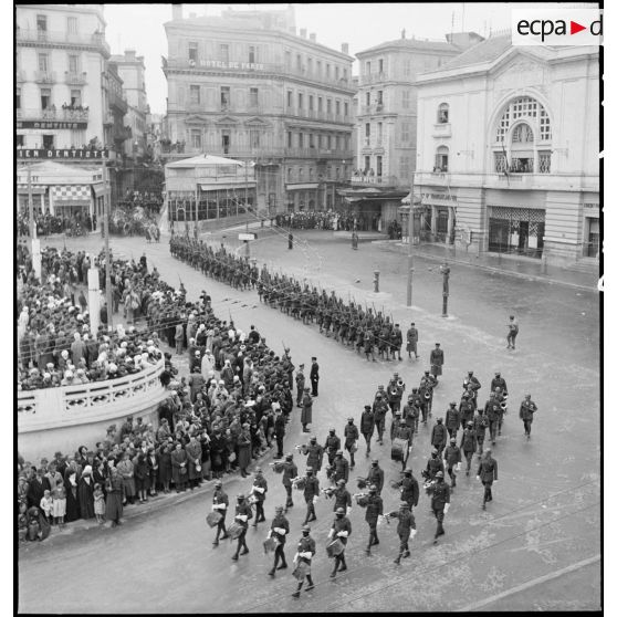 Cérémonie d'obsèques du général de division Marie-Joseph Welvert, commandant la DMC (division de marche de Constantine) : vue en plongée sur une musique de tirailleurs sénégalais ouvrant le défilé du cortège funèbre.