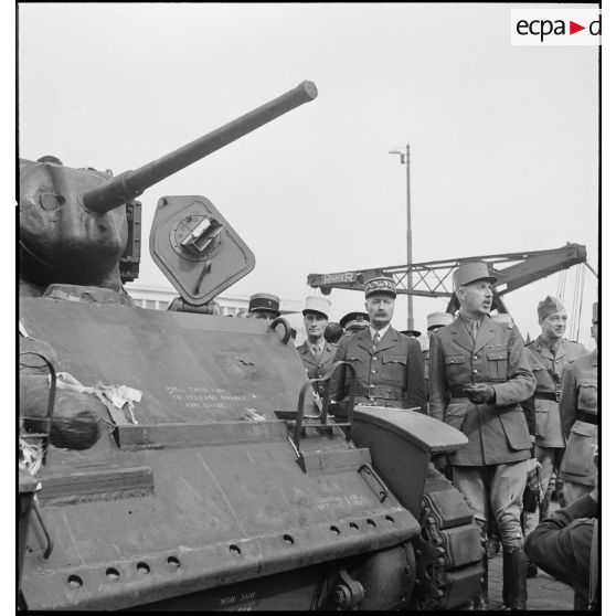 Sur une chaîne de montage sur le port d'Alger, le général de division Roger Leyer, aide-major général chargé de l'organisation, donne des informations concernant un char léger Suart M5A1 au général d'armée Henri Giraud, commandant en chef civil et militaire, dans le cadre du réarmement de l'armée française par les Etats-Unis.