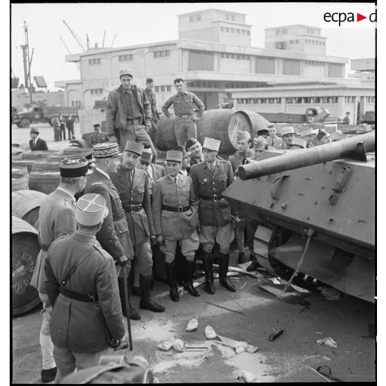 Sur une chaîne de montage sur le port d'Alger, le général de division Roger Leyer, aide-major général chargé de l'organisation, donne des informations concernant un chasseur de chars TD M10 au général d'armée Henri Giraud, commandant en chef civil et militaire, dans le cadre du réarmement de l'armée française par les Etats-Unis.