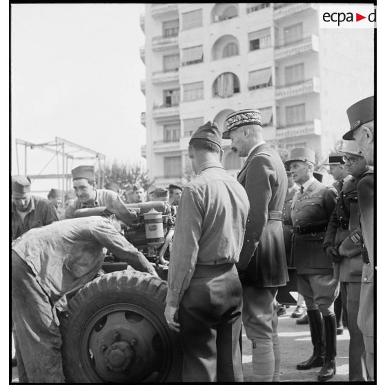 Dans le cadre du réarmement de l'armée française par les Etats-Unis, sur une chaîne de montage sur le port d'Alger, un colonel de l'armée de l'air américaine présente le montage d'un moteur de véhicule au général d'armée Henri Giraud, commandant en chef civil et militaire.
