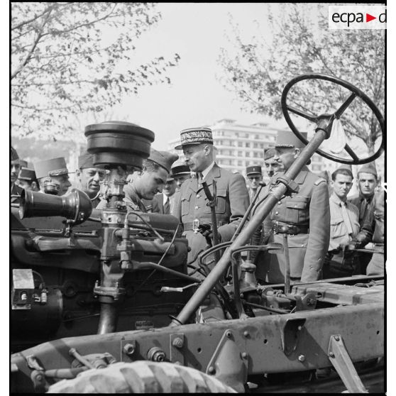 Dans le cadre du réarmement de l'armée française par les Etats-Unis, sur une chaîne de montage sur le port d'Alger, un colonel de l'armée de l'air américaine présente un châssis de véhicule au général d'armée Henri Giraud, commandant en chef civil et militaire.