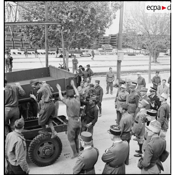 Le général d'armée Henri Giraud, commandant en chef civil et militaire, en compagnie du général de division Roger Leyer, aide-major général chargé de l'organisation et du général d'armée René Prioux, major général des forces terrestres et aériennes, assistent au montage de la caisse d'un camion GMC sur son châssis.