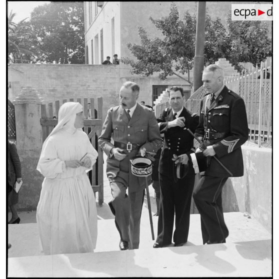 Le général d'armée Henri Giraud, commandant en chef civil et militaire, accompagné du colonel François Gonzalez de Linarès, sous-chef d'état-major, et du lieutenant de vaisseau Viret, s'enretient avec une soeur de l'orphelinat Notre-Dame d'Afrique, cible d'un bombardement dans la nuit du 17 au 18 avril 1943.