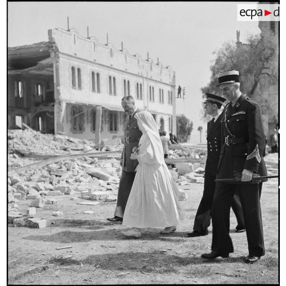Le général d'armée Henri Giraud, commandant en chef civil et militaire, accompagné du colonel François Gonzalez de Linarès, sous-chef d'état-major, et du lieutenant de vaisseau Viret, s'enretient avec une soeur de l'orphelinat Notre-Dame d'Afrique, cible d'un bombardement dans la nuit du 17 au 18 avril 1943.
