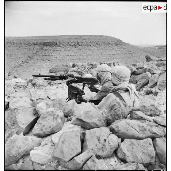 Mise en batterie d'une mitrailleuse Hotchkiss, modèle 1914, par des méharistes du groupement du capitaine Paganelli dans le secteur du FSEA. (Front sud-est algérien), entre le col de Bir el Asker et le Chott el Jerid.