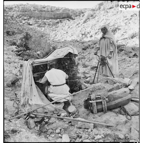 Deux méharistes du groupement Paganelli utilisent un central téléphonique dans le secteur du Chott el Jerid, sur le FSEA (Front sud-est algérien). Le méhariste à droite actionne la génératrice à manivelle.