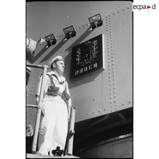 Portrait en contre-plongée d'un quartier-maître de 1re classe à bord du croiseur Jeanne d'Arc, amarré dans le port d'Alger.