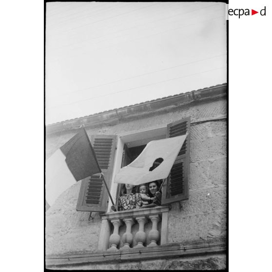 Des femmes pavoisent, avec les drapeaux français et corse, la fenêtre d'une maison de la commune de Saint-Florent qui vient d'être libérée.