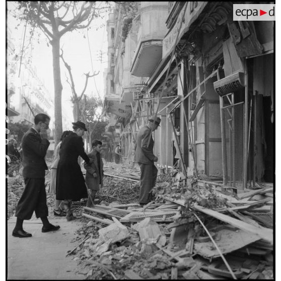 Des civils sortant d'un abri souterrain après le bombardement allemand visant l'aérodrome Maison-Blanche à Alger, dans la nuit du 20 au 21 novembre 1942, reviennent dans leur immeuble endommagé rue d'Isly.