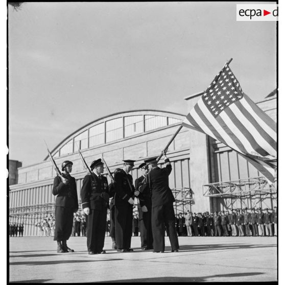 Pendant la cérémonie sur l'aérodrome de Maison-Blanche à Alger en l'honneur du GC II/5 La Fayette, le commandant Constantin Rozanoff, commandant le groupe de chasse, remet symboliquement le drapeau des Etats-Unis au lieutenant Pierre Le Gloan, porte-drapeau.