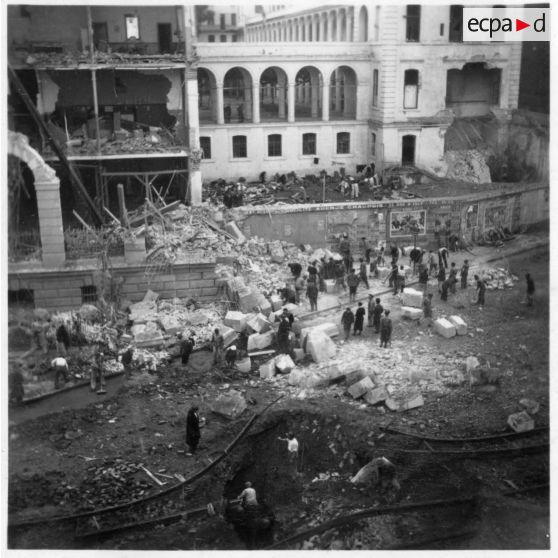 Vue en plongée sur le cratère de bombe causé lors du  bombardement allemand d'Alger du 24 novembre 1942, détruisant les rails du tramway et la façade du lycée Bugeaud.