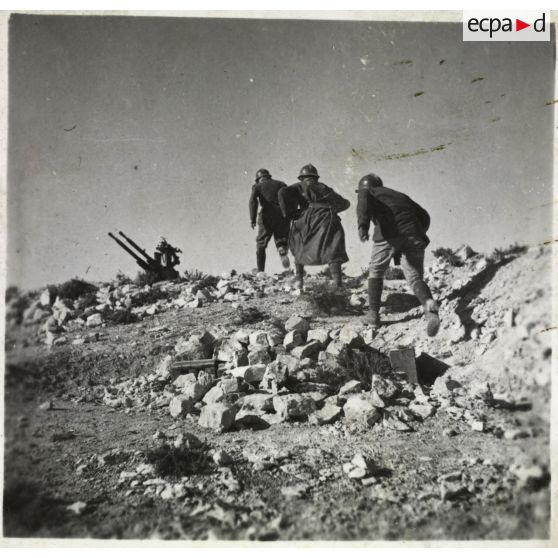 Des artilleurs du 411e RAAA (régiment d'artillerie antiaérienne) courent vers leur mitrailleuse antiaérienne Hochkiss 13,2 mm sur affût bitube.