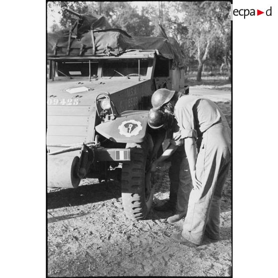 L'équipage du half-track M3 radio Fomalhaud du 2e escadron du 12e régiment de chasseurs d'Afrique (12e RCA) de la 2e division blindée (2e DB) examine une roue du véhicule.