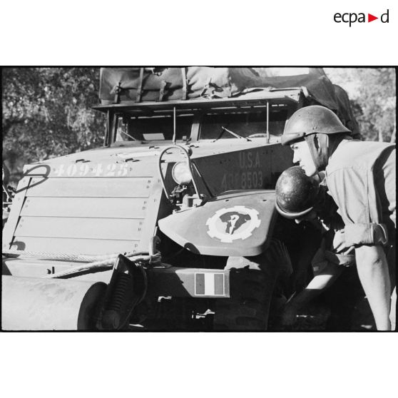 L'équipage du half-track M3 radio Fomalhaud du 2e escadron du 12e régiment de chasseurs d'Afrique (12e RCA) de la 2e division blindée (2e DB) examine une roue du véhicule.