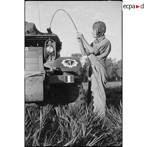 Un chasseur, membre d'équipage du half-track M3 radio Fomalhaud du 12e régiment de chasseurs d'Afrique (12e RCA)) de la 2e division blindée (2e DB), examine l'antenne radio de son véhicule.