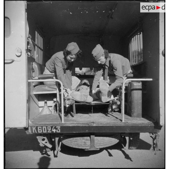 Deux conductrices ambulancières du 27e escadron du Train installent un blessé dans une ambulance Renault AGC 3.