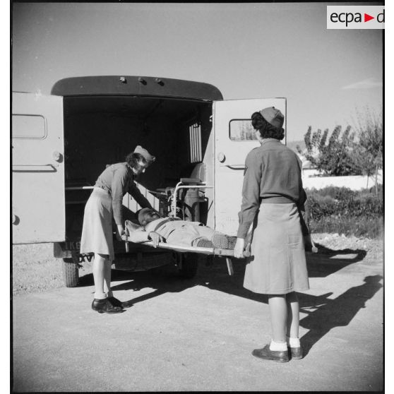 Des conduct'rices ambulancières du 27e escadron du Train brancardent un blessé dans une ambulance Renault AGC 3.