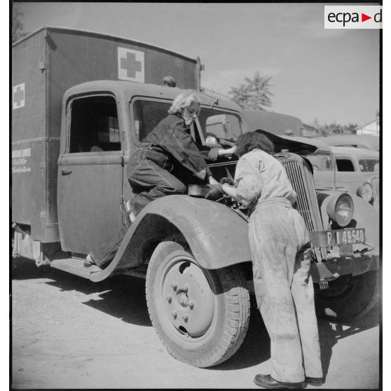 De retour de mission, des conductrices ambulancières du 27e escadron du Train assurent l'entretien du moteur de leur ambulance Renault AGC 3.