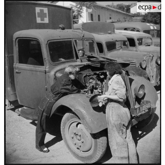 De retour de mission, des conductrices ambulancières du 27e escadron du Train assurent l'entretien du moteur de leur ambulance Renault AGC 3.