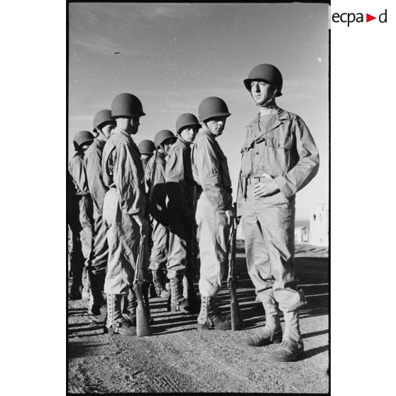 Rassemblement sur les rangs de soldats de la 2e division blindée (2e DB), équipés de tenues américaines, lors d'une inspection de la division.