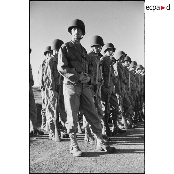 Rassemblement sur les rangs de soldats de la 2e division blindée (2e DB), équipés de tenues américaines, lors d'une inspection de la division.
