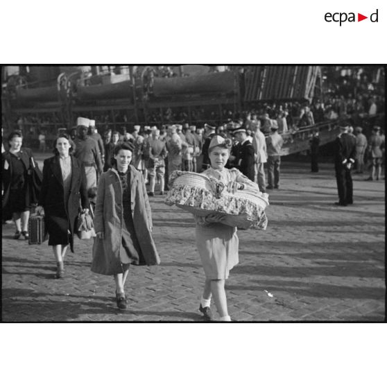 Une infirmière de la Croix-Rouge porte dans les bras un couffin dans le port de Casablanca.