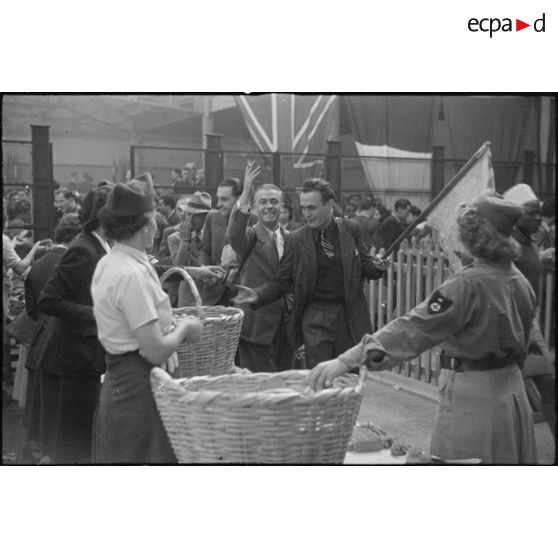 Distribution de sandwichs par des femmes de la Croix-Rouge à des réfugiés français joyeux dans le grand hall de la gare maritime de Casablanca.