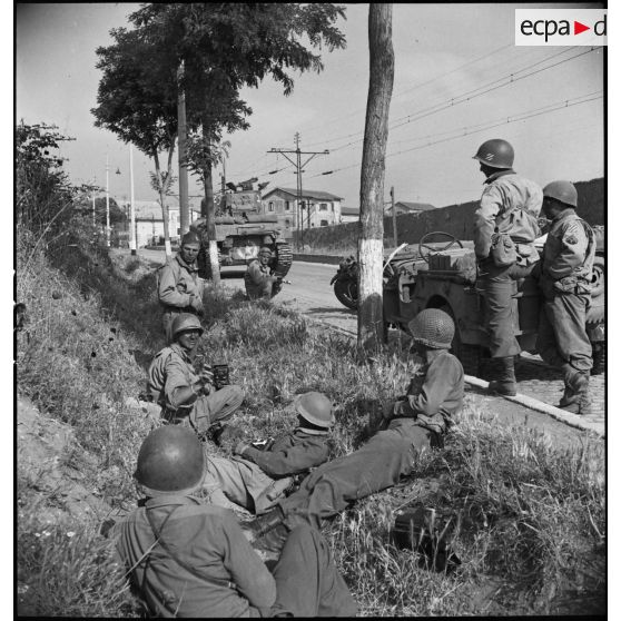 A l'entrée de Rome, des correspondants de guerre, cameramen et photographes français, américains, britanniques ou canadiens (SCA, signal corps, AFPU), s'abritent de rafales de mitrailleuses allemandes. Au second plan, accroupi, le caméraman Raymond Méjat.