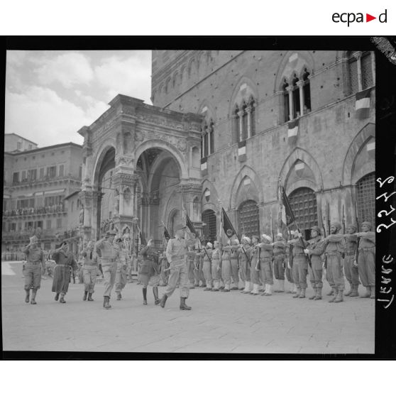 Lors d'une cérémonie, le général d'armée Alphonse Juin, commandant le corps expéditonnaire français (CEF), accompagnés de ses grands subordonnés, salue les drapeaux des unités alignés sur la Piazza del Campo à Sienne.