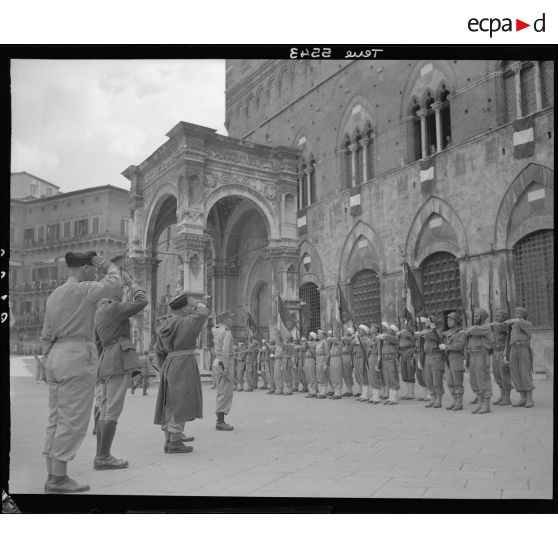 Lors d'une cérémonie, le général d'armée Alphonse Juin, commandant le corps expéditonnaire français (CEF), accompagnés de ses grands subordonnés, salue les drapeaux des unités alignés sur la Piazza del Campo à Sienne.