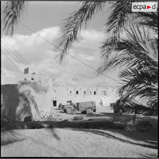 Eléments de transport de la 75e CRD (compagnie de réparation divisionnaire) groupés devant les bâtiments.