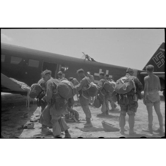 Des parachutistes de la 1.Fallschirm-Jäger-Division s'équipent de leur parachute avant de monter à bord d'un avion de transport Junkers Ju-52.