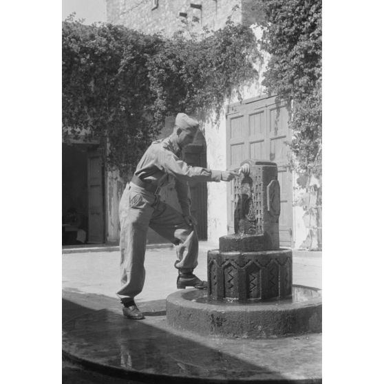 En Libye, le reporter Werner Bockelmann de la 7e compagnie de propagande de l'armée de l'air allemande (Luftwaffe Kriegsberichter Kompanie 7) devant une fontaine du souk de Derna.