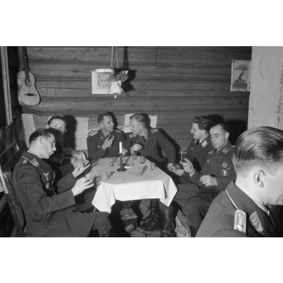 Des officiers de la Luftwaffe lors d'un repas, un sous-officier joue de l’accordéon.