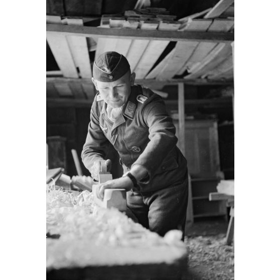 Un officier (Oberleutnant) membre d'un équipage de bombardier utilise un rabot.