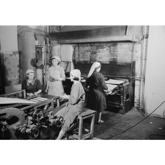Des femmes russes travaillent dans une buiscuiterie sous le contrôle des contre-maitres allemands.