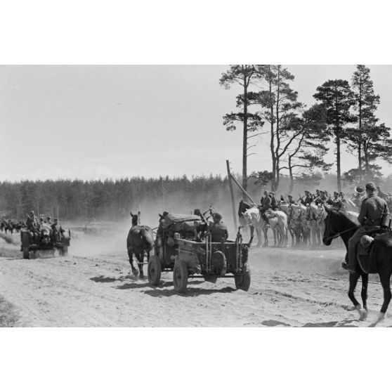 Une charrette hippomobile dotée de deux mitrailleuses MG-34 jumelées Maschinengewehrwagen 36 (If. 5), lors d'un défilé rythmé par le corps de musique du 83e régiment d'artillerie (évoluant au sein de la 83e division d'infanterie).