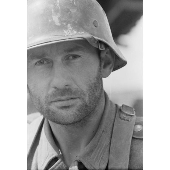 Portrait d'un fantassin casqué en poste dans une tranchée défensive allemande.