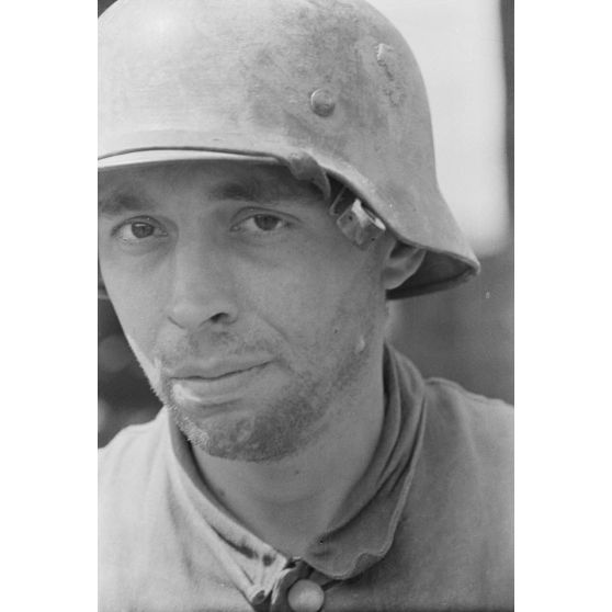 Portrait d'un fantassin casqué en poste dans une tranchée défensive allemande.