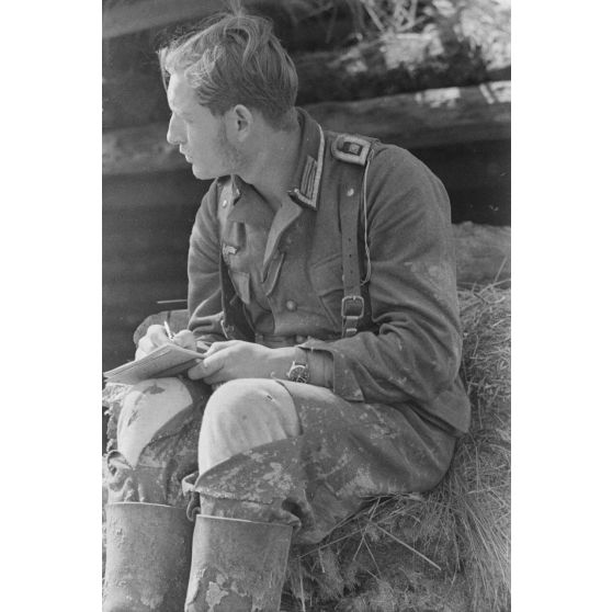 Un sous-officier allemand, en poste dans une tranchée défensive, rédige une lettre (courrier).