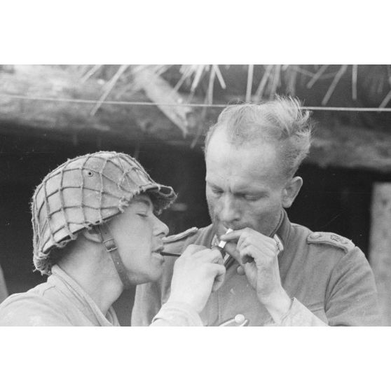 Dans une tranchée défensive allemande, un officier et un fantassin allemand partagent du feu.