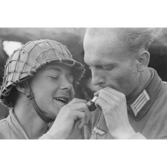 Dans une tranchée défensive allemande, un officier et un fantassin allemand partagent du feu.