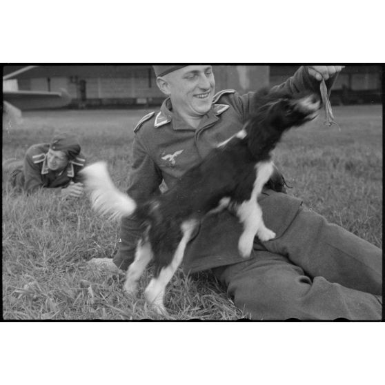 En Norvège, sur l'aérodrome de Stavanger-Sola, lors d'une démonstration 8./LLG 1 (Lulftlandegeschwader 1), un sous-officier joue avec un chien, mascotte de l'unité.