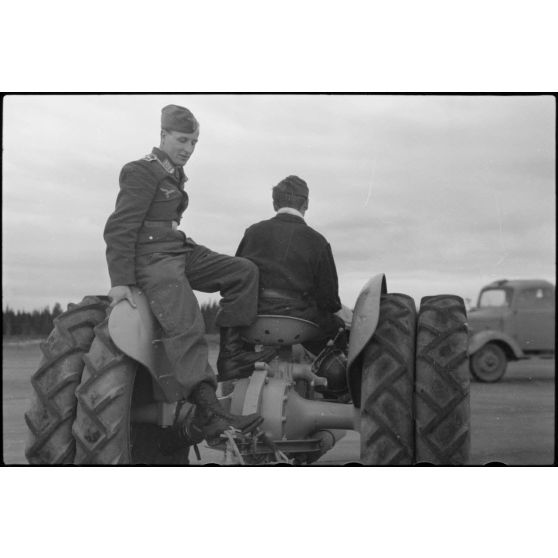 Sur la piste du terrain d'aviation, un tracteur agricole tracte le planeur DFS-230 du Luftlandegeschwader 1 (8./LLG 1) vers un nouvel emplacement. Le planeur est baptisé "Sieg" (immatriculation LB+1-92).