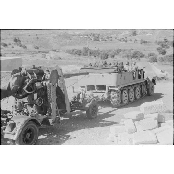 Un semi-chenillé Sd.kfz.7 s'apprête à tracter une pièce de 8,8 cm FlaK que les artilleurs viennent d'atteler.