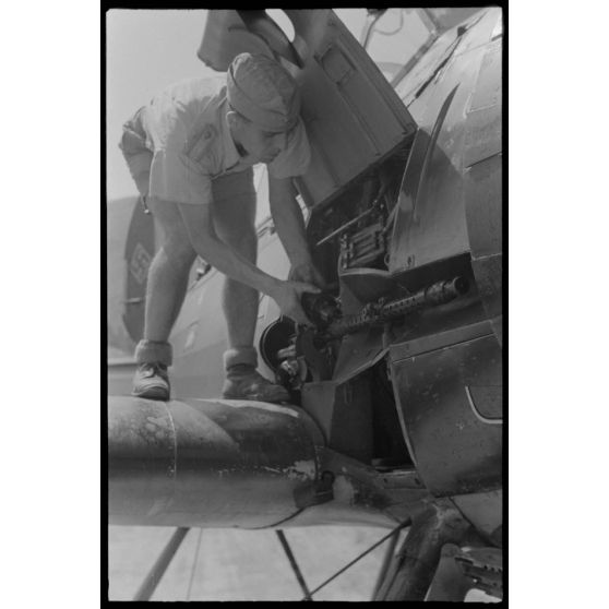 Sur la base de Skaramangas occupée par le 1er groupe du Seeaufklärungsgruppe 126, des mécaniciens approvisionnent la mitrailleuse MG-17 située sous le capot moteur de l'Arado Ar-196.